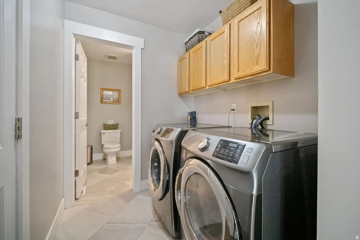 Dedicated laundry area featuring overhead natural wood cabinetry, a utility countertop, and tile flooring