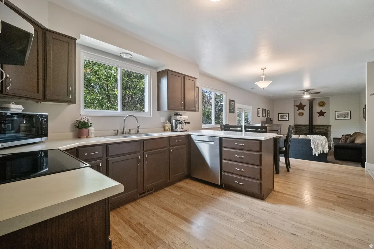 Open-concept kitchen featuring wood-finish flooring, dark wood cabinetry, and light-toned countertops
