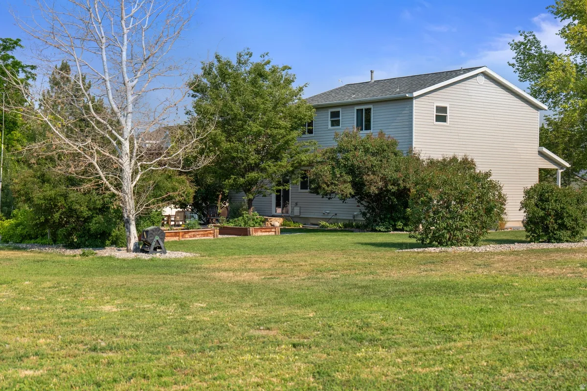 Spacious backyard featuring a lush lawn, mature trees, and raised garden beds