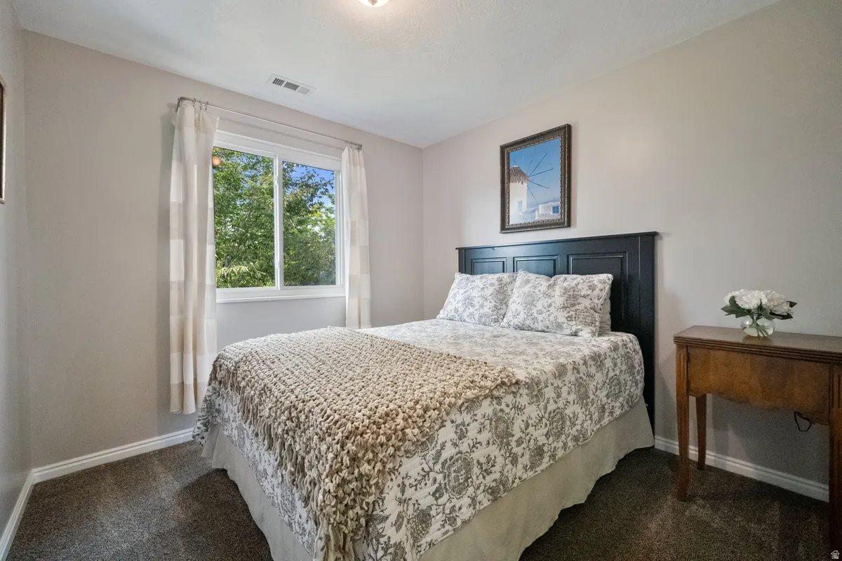 Bedroom featuring a large double window, light gray wall paint, white trim, and dark gray carpeting