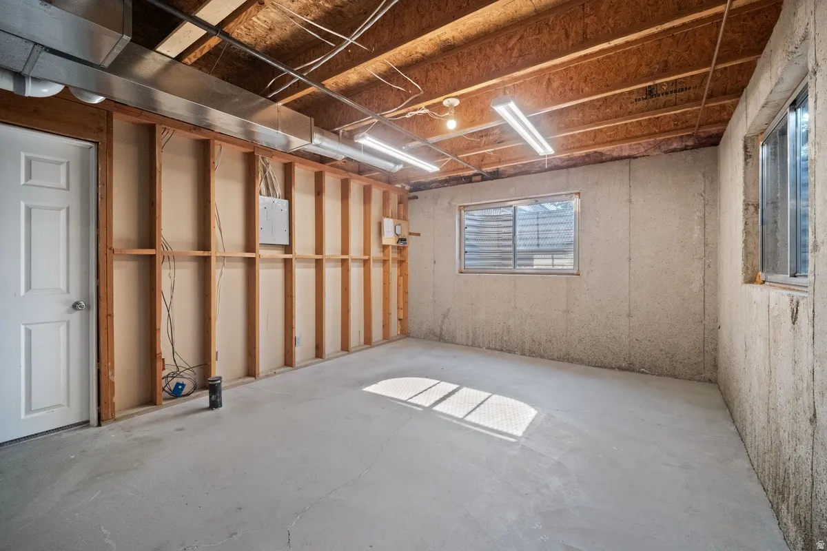 Unfinished basement space featuring exposed wood framing, a concrete floor, and multiple windows allowing natural light
