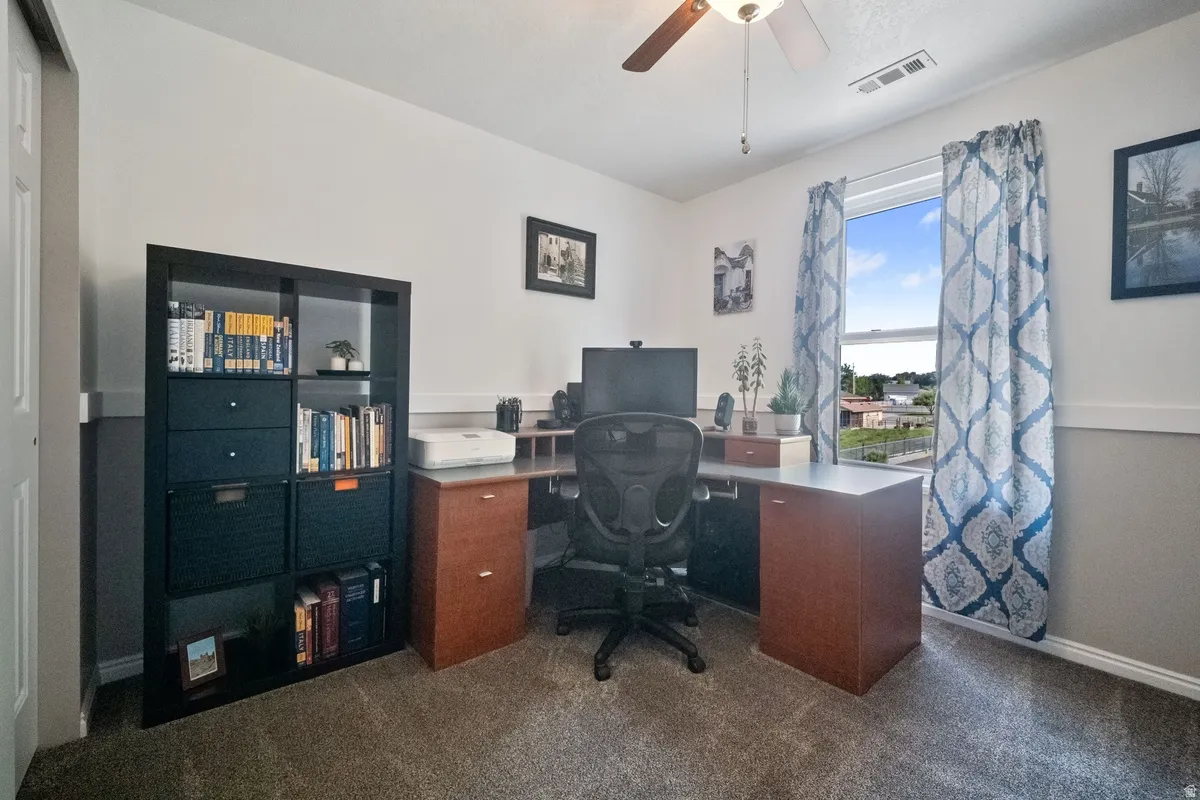 Bedroom featuring a window with exterior views, overhead ceiling fan, and carpeted flooring