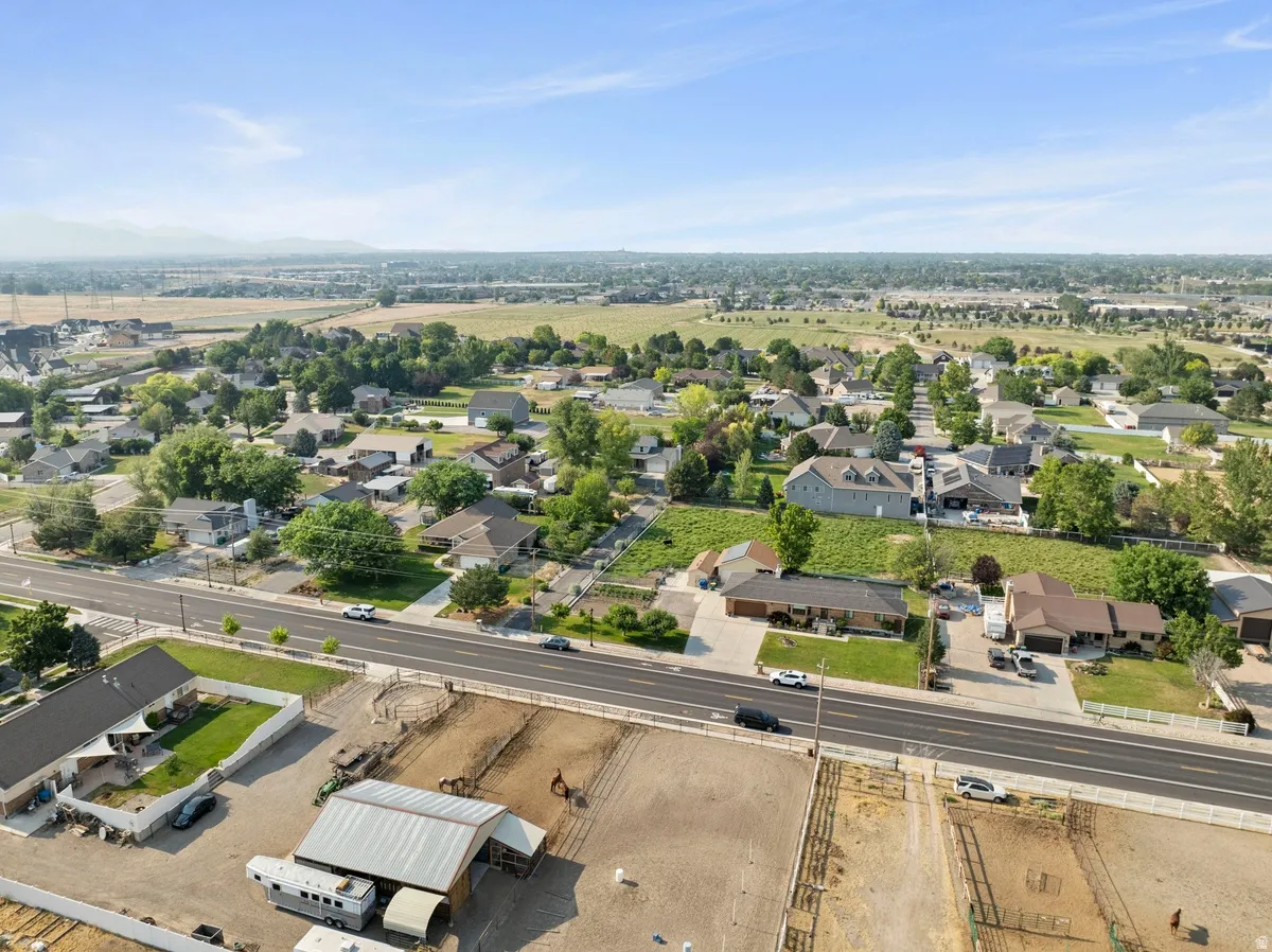 Expansive rural property featuring an equestrian facility with multiple fenced pastures, a covered stable structure, and a round pen