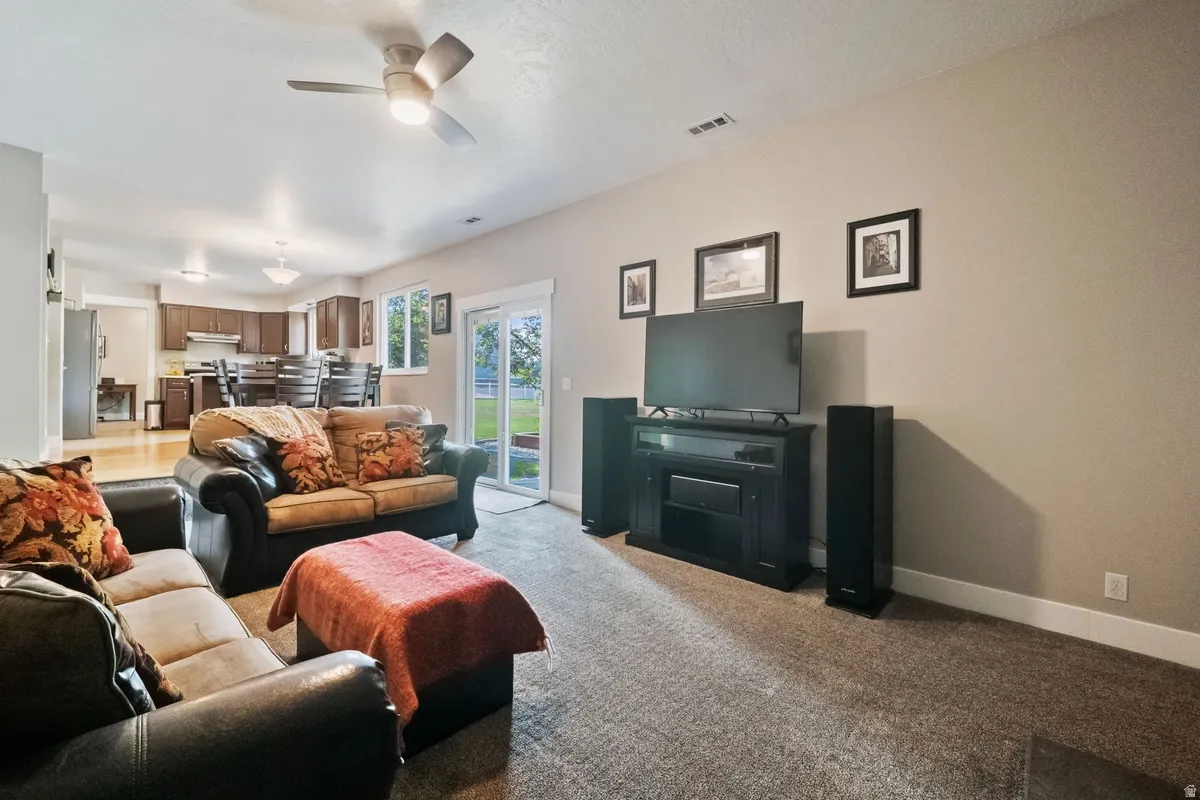 Open-concept living space featuring a ceiling fan, carpeted flooring, and neutral wall tones
