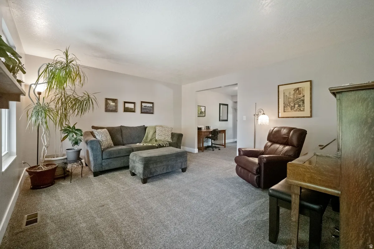 Spacious living area featuring light gray wall paint, textured ceiling, and gray carpeting