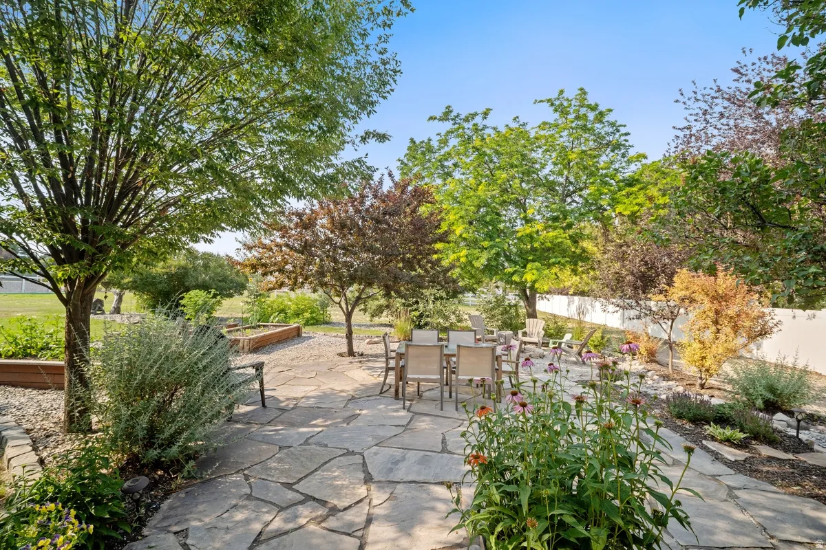Expansive flagstone patio area surrounded by mature trees and varied plantings