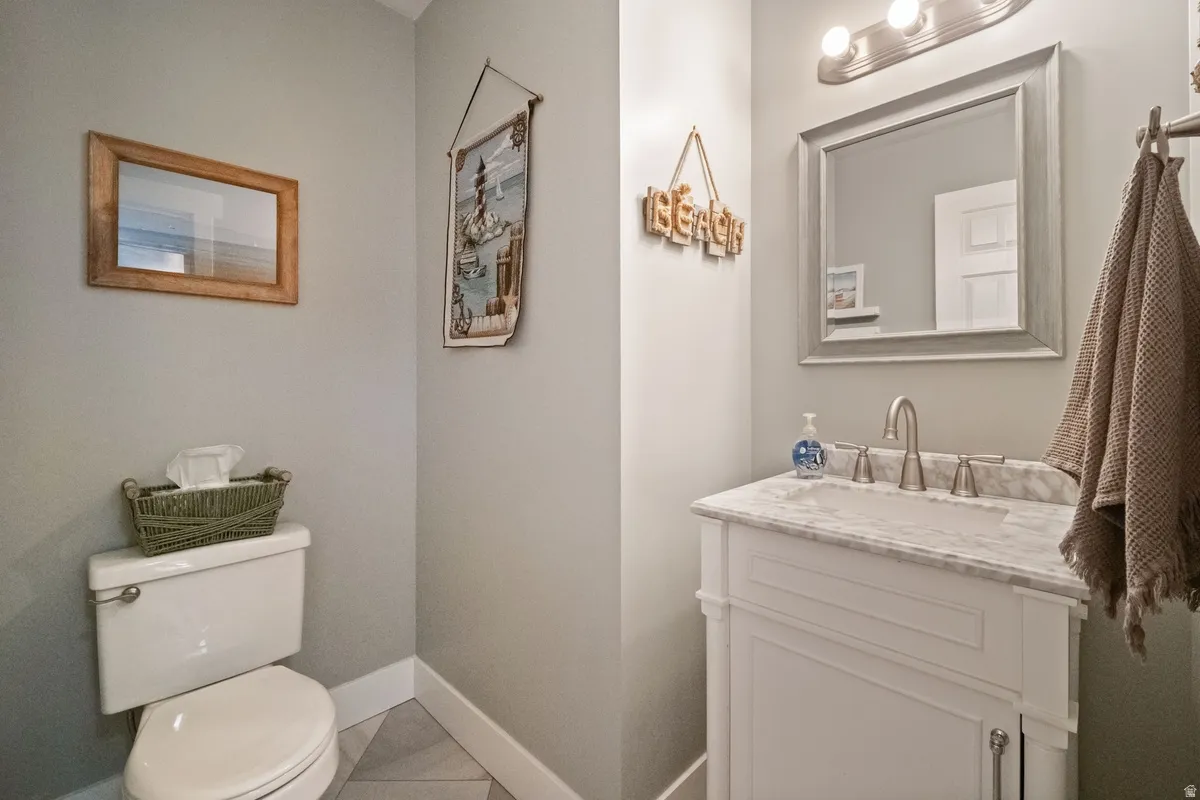Bathroom featuring a white vanity with a marble countertop and undermount sink, brushed nickel faucet, and a wall-mounted mirror with a gray frame