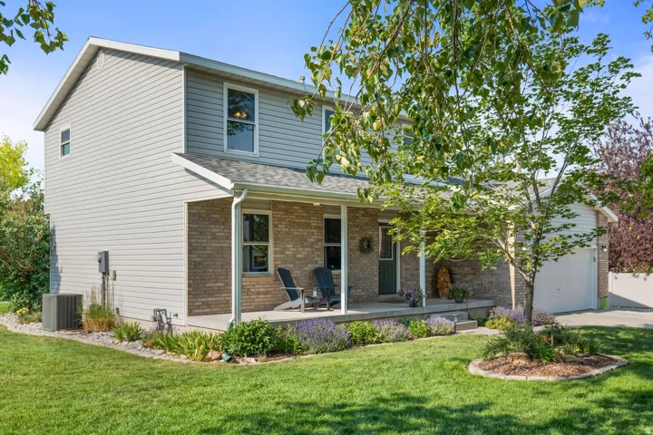 Two-story residence featuring light gray siding and brick accents