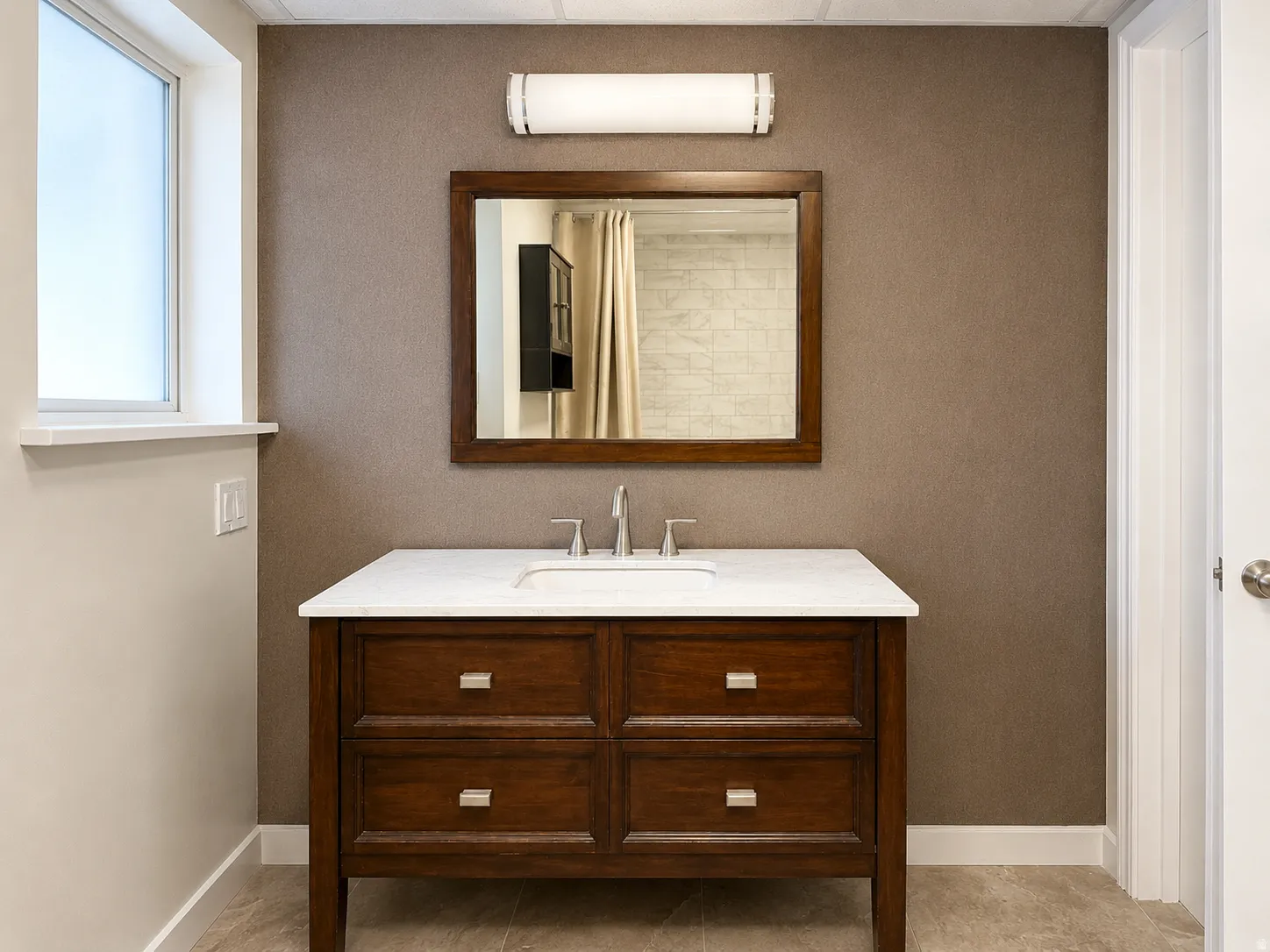 Dark wood vanity with a white countertop, featuring a rectangular undermount sink and a polished chrome faucet