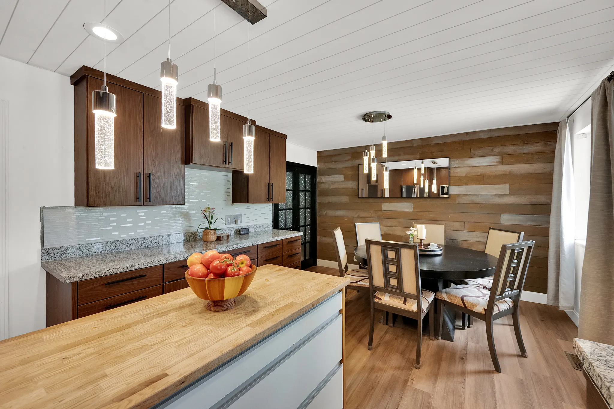 Kitchen and dining area featuring a wood-finish accent wall, wood-finish flooring, and a shiplap ceiling