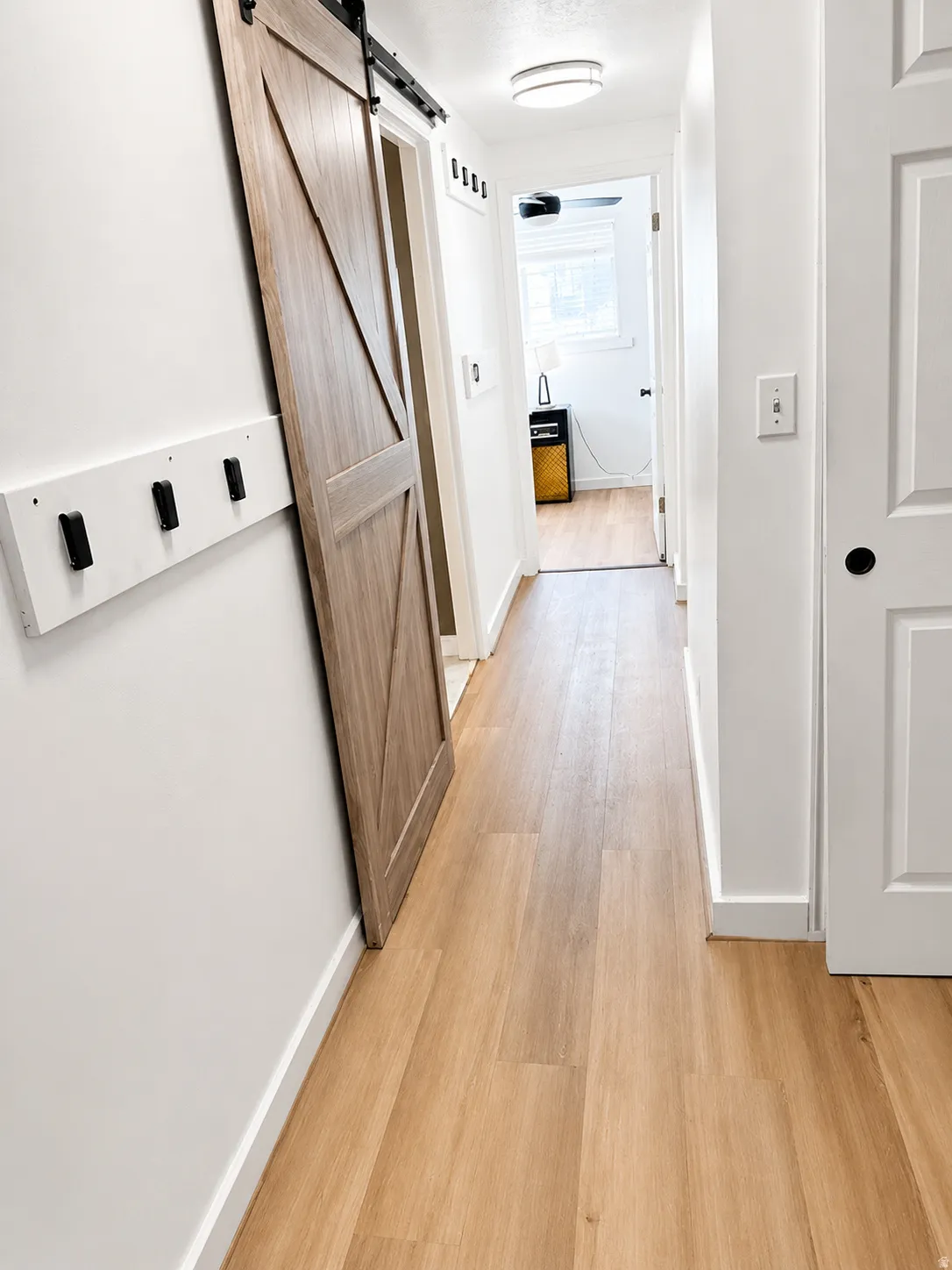 Wood-finish flooring throughout, complemented by a modern barn door with black hardware, white walls, and recessed lighting