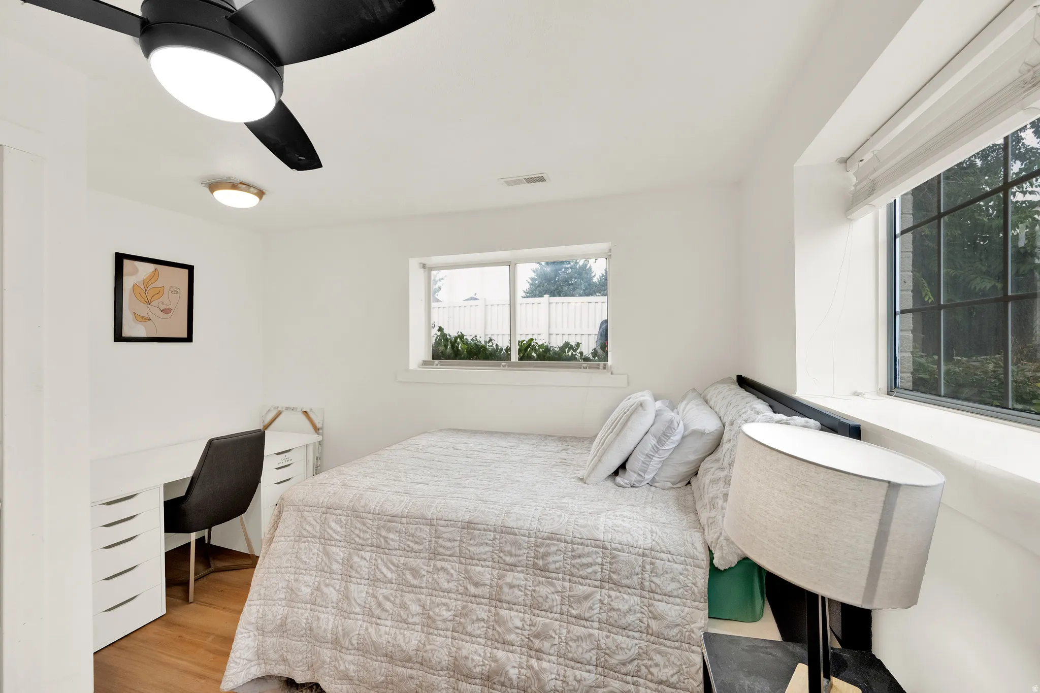 Bedroom featuring a ceiling fan with integrated lighting, wood-finish flooring, and white walls