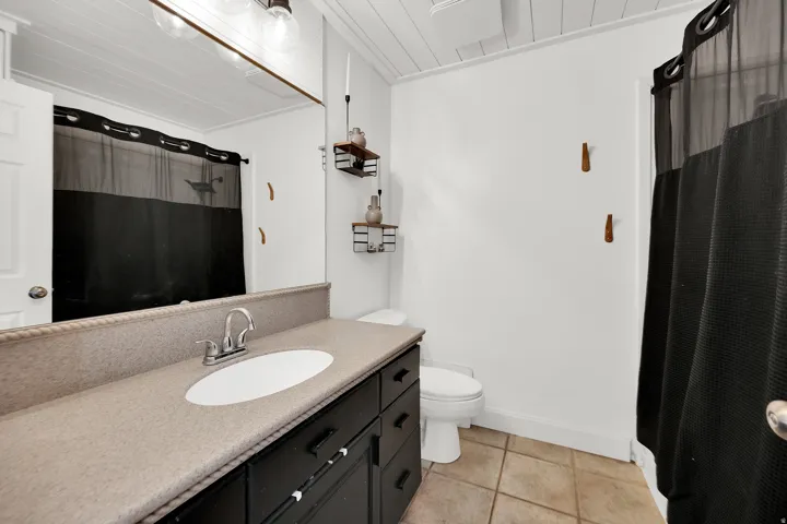 Bathroom featuring a black vanity with a light-toned countertop, a white oval sink, and a chrome faucet