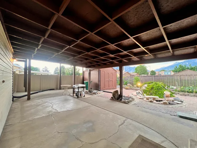 Expansive covered patio featuring a grid-patterned ceiling, concrete flooring, and an integrated brick-paver garden area