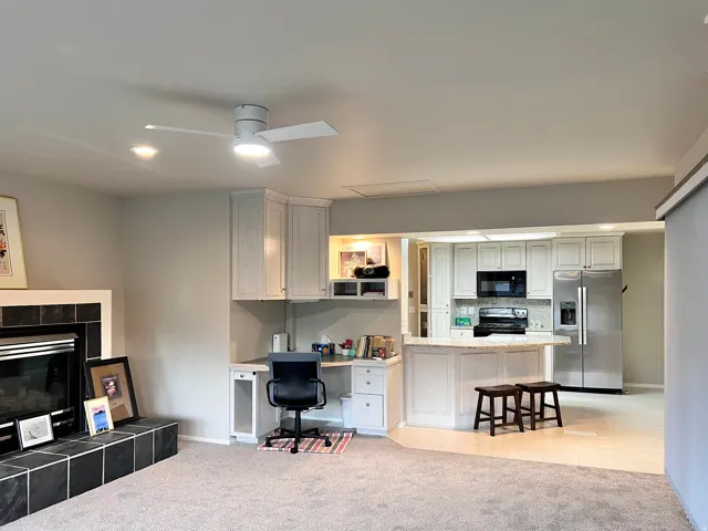 Open-concept living area featuring a kitchen with white cabinetry and stainless steel appliances