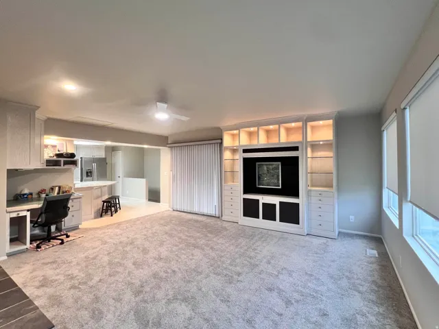 Spacious living area featuring light gray carpeting and a ceiling fan
