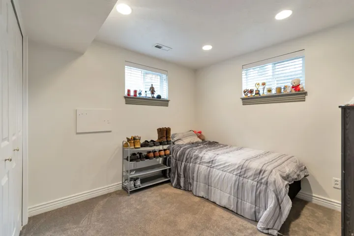 Carpeted room featuring recessed lighting, two windows with blinds, and white bi-fold closet doors
