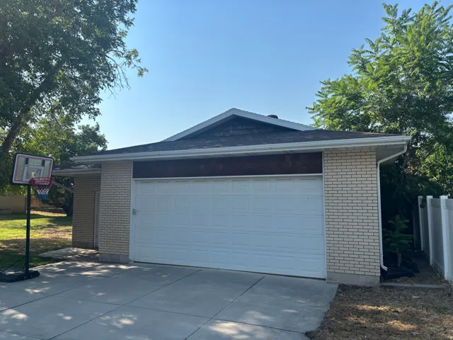 Modern brick garage featuring a spacious single-car design with a sectional overhead door, pitched roofline, and concrete driveway
