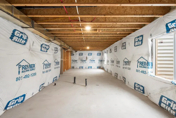 Unfinished basement with concrete flooring, exposed wood ceiling joists, and visible plumbing rough-ins