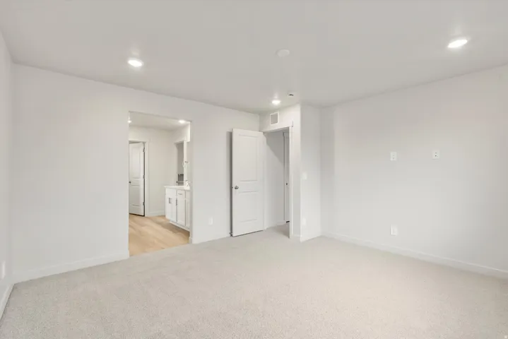 Spacious room featuring light-colored carpet flooring, recessed lighting, and white walls