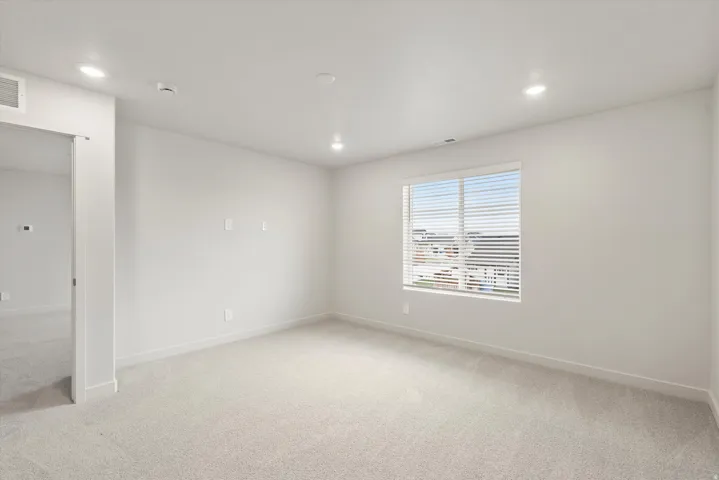 Bright room with recessed lighting and light-toned carpet flooring