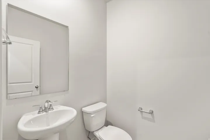 Pedestal sink with chrome fixtures and a rectangular mirror