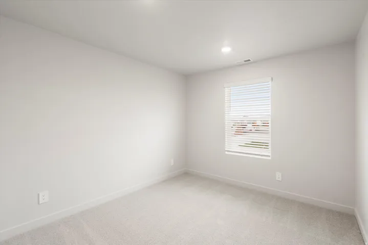 Carpeted interior space featuring recessed lighting, a single window with blinds, and white wall finishes with matching trim