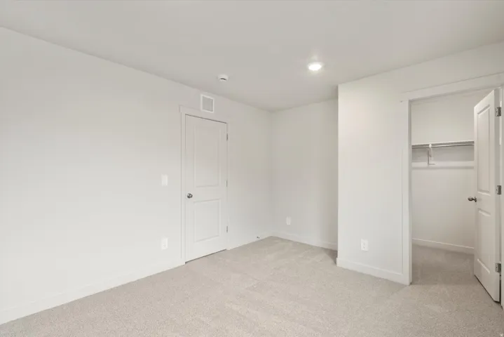 Neutral-toned bedroom featuring wall-to-wall carpeting, recessed ceiling lighting, and a closet with shelving and hanging rod
