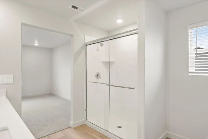 Modern bathroom featuring a glass-enclosed shower with white subway tile, a white shower pan, and a built-in corner shelf