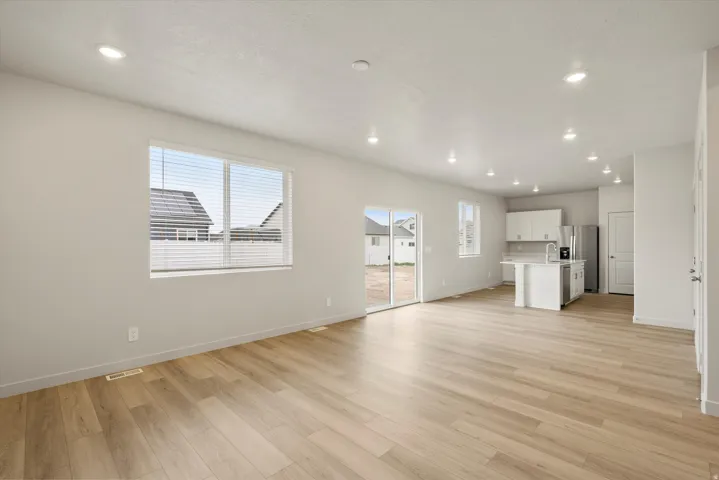 Open-concept living space featuring light wood-finish flooring, recessed lighting, and a neutral wall palette