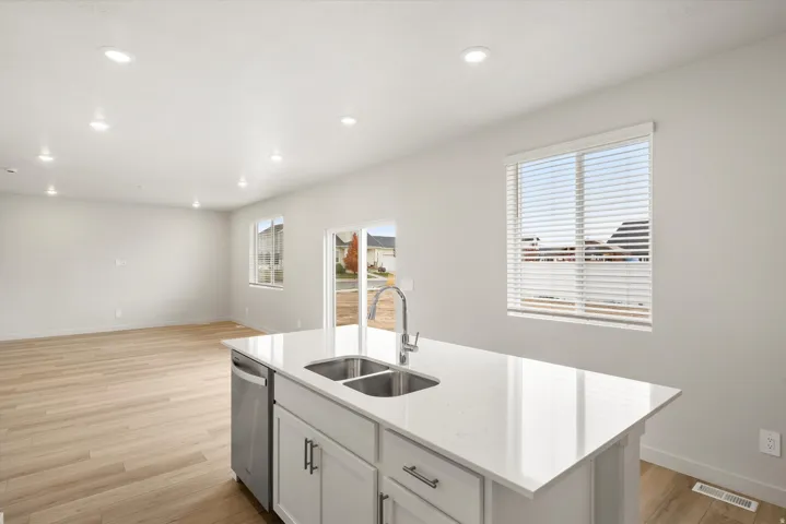 Kitchen island featuring a double-basin stainless steel sink, gooseneck faucet, and white countertop