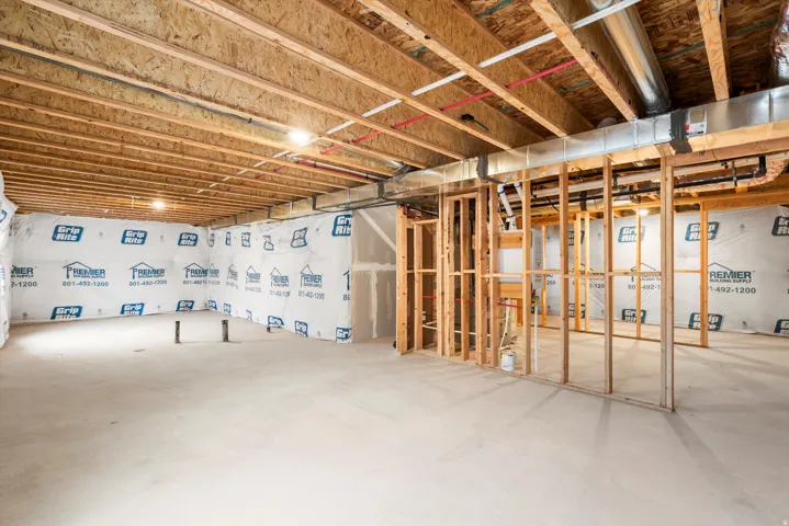 Unfinished basement space featuring a concrete floor and exposed wooden ceiling joists