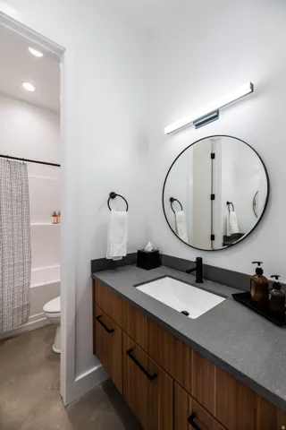 Floating wood-finish vanity with a rectangular undermount sink, dark countertop, and matte black faucet