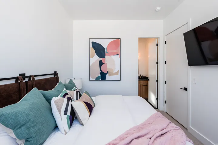 White walls with a contrasting brown headboard and a built-in wall-mounted television