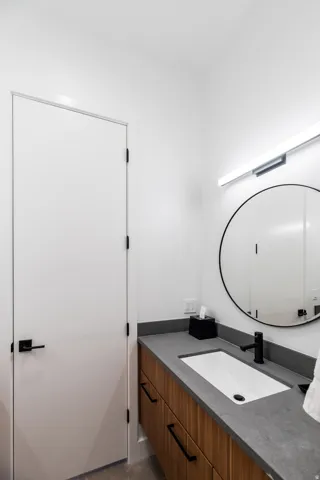 Contemporary bathroom featuring a floating wood-finish vanity with a dark countertop, an integrated rectangular sink, and a matte black faucet
