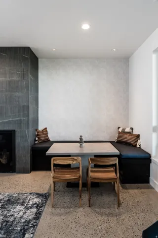 Built-in banquette seating with a square table, adjacent to a fireplace with textured tile surround