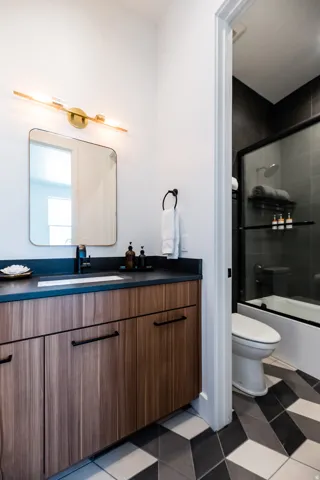 Bathroom vanity featuring wood-finish cabinetry, a dark countertop with an integrated sink, and matte black hardware