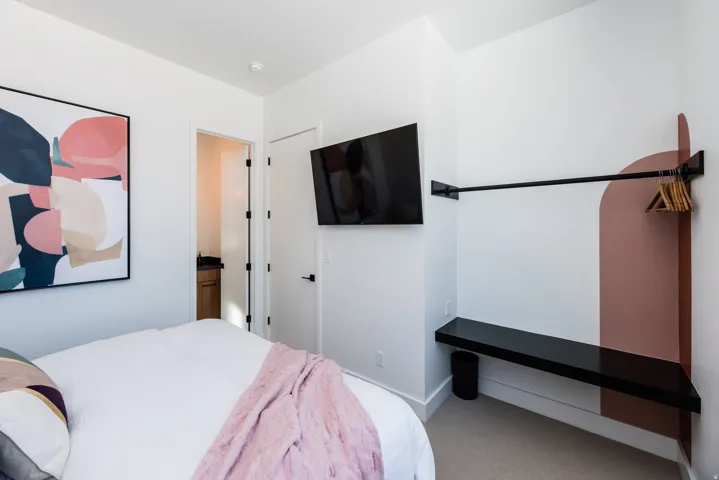 Bedroom featuring a wall-mounted television, a built-in hanging rod, and a floating corner shelf