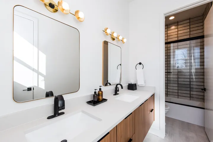 Dual vanity with white undermount sinks, matte black faucets, and light wood-finish cabinetry