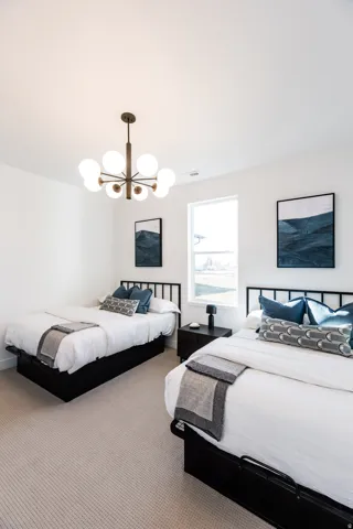 Bright room featuring a modern multi-bulb chandelier, soft textured carpeting, and a large window providing ample natural light
