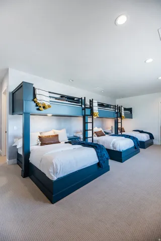 Spacious room featuring three built-in bunk bed structures with integrated ladders, recessed lighting, and light-colored carpeting