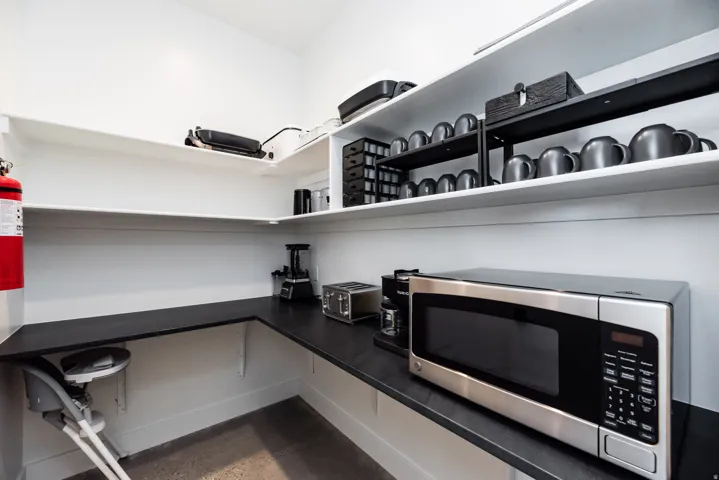 Spacious pantry featuring white walls, wrap-around black countertops, and multiple levels of white shelving