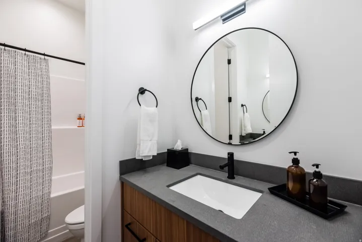 Bathroom featuring a wood-finish vanity with a built-in rectangular sink, a dark countertop, and matte black fixtures