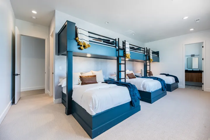 Custom built-in bunk beds with individual lighting fixtures, light-toned carpeting, recessed ceiling lighting, and crisp white walls