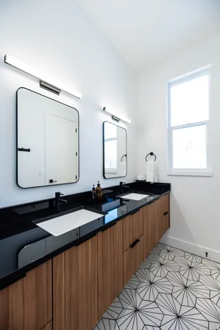 Floating double vanity with wood-finish cabinetry, black countertops, and integrated rectangular sinks