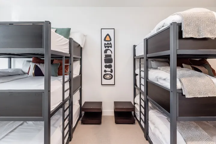 Room featuring two sets of triple bunk beds with metal frames, plush carpeting, and recessed lighting