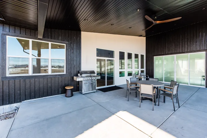 Spacious covered patio featuring concrete flooring, a dark plank ceiling, and recessed lighting