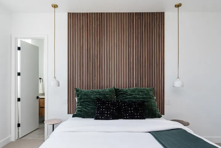 Accent wall with vertical wood paneling, featuring two brass-finished pendant lights with white shades