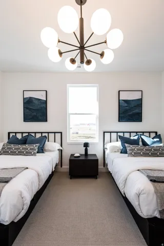 Carpeted bedroom featuring a central window, white walls, and a modern chandelier