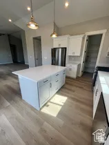 Kitchen featuring a central island with white cabinetry, stainless steel appliances, and wood-finish flooring